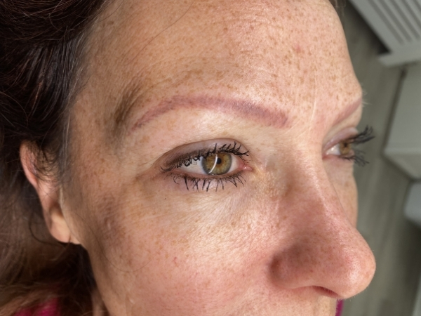 Voorfoto van permanente wenkbrauwen en eyeliner vóór een PMU-correctie.